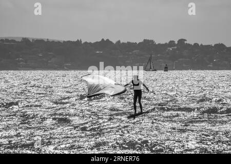 Hill Head Angleterre - août 20 2023 : planche à voile en noir et blanc avec l'île de Wight en arrière-plan Banque D'Images