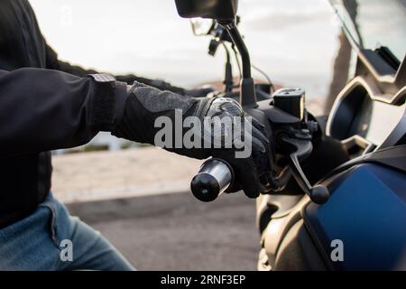 Gros plan de la main d'un motard avec un gant de protection tenant le guidon de son scooter Banque D'Images