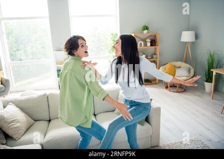 Photo de deux jolies jeune dame joyée chill divertissement dansant spacieux salon appartement à l'intérieur Banque D'Images