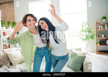 Photo de deux jolies personnes positives joyées dansant profiter de l'appartement de passe-temps de week-end de fête domestique à l'intérieur Banque D'Images