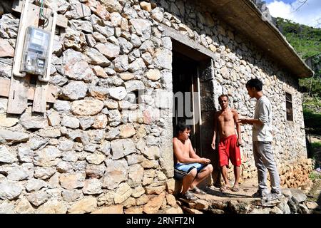 (160823) -- DAHUA, Aug. 23, 2016 -- Lan Zhiping (R) encourages villagers to raise chickens in Nongxiong Village, Dahua Yao Autonomous County, south China s Guangxi Zhuang Autonomous Region, Aug. 16, 2016. Nongxiong Village, located in mountainous areas of Guangxi, has 123 families living under poverty standard among its nearly 2000 villagers. Lan Zhiping, 28 years old, has found out a way to lift villagers out of poverty through chicken raising industry. This year, he established a poultry raising cooperative with four other villagers, in which more than 2,300 chickens are raised. A hatching b Stock Photo