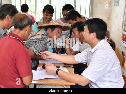 (160823) -- DAHUA, 23 août 2016 -- LAN Zhiping (2nd R) répond aux questions des villageois lors d'une réunion de villageois dans le village de Nongxiong, comté autonome de Dahua Yao, région autonome de Guangxi Zhuang, sud de la Chine, 17 août 2016. Le village de Nongxiong, situé dans les zones montagneuses du Guangxi, compte 123 familles vivant sous le niveau de pauvreté parmi ses près de 2000 villageois. LAN Zhiping, 28 ans, a trouvé un moyen de sortir les villageois de la pauvreté grâce à l’élevage de poulets. Cette année, il a créé une coopérative d'élevage de volailles avec quatre autres villageois, dans laquelle plus de 2 300 poulets a Banque D'Images