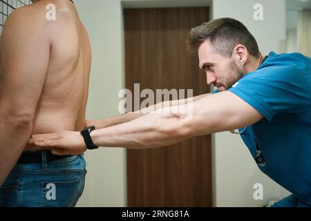 Physiothérapeute qualifié effectuant la palpation lombaire chez le patient Banque D'Images