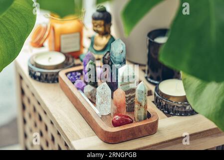 Divers minéraux et cristaux curatifs sur un plateau en bois, statuette de bouddha et bougies en gros plan. Concept de méditation. Banque D'Images