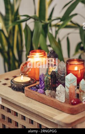 Divers minéraux et cristaux curatifs sur un plateau en bois, statuette de bouddha et bougies en gros plan. Concept de méditation. Banque D'Images