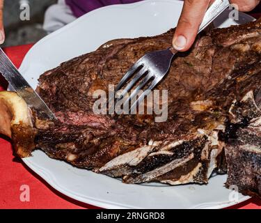 Maîtrise culinaire : les mains des femmes se tranchent dans le succulent barbecue Rib Steak avec précision Banque D'Images