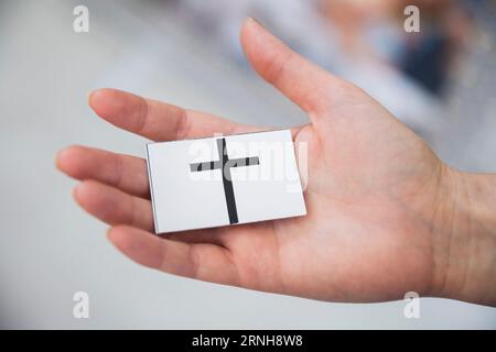 Berlin, Allemagne. 27 août 2023. Une femme tient la carte d'un jeu de mémoire avec la croix du christianisme au 6e Festival des religions de Berlin. (Scène posée) crédit : Christoph Soeder/dpa/Alamy Live News Banque D'Images