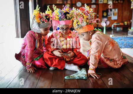 (170405) -- MAE HONG SON, 5 avril 2017 -- les garçons jouent avec un téléphone intelligent alors qu'ils visitent Wat Pratthat Doi Kongmu pendant les rituels d'ordination des moines novices POI sang long dans le nord de la Thaïlande, Mae Hong son, 1 avril 2017. Considéré comme l'un des plus grands moments de la vie d'un garçon, les rituels d'ordination des moines novices POI sang long sont organisés chaque année par les peuples Shan, également connus sous le nom de Tai Yai, qui résident principalement au Myanmar et dans le nord de la Thaïlande. Âgés entre 7 et 14 ans, les garçons, appelés sang long en langue shan, subiront une série de procédures rituelles au cours d’un POI sang long typique Banque D'Images