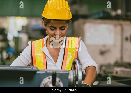 Technicien ingénieur africain femme peau noire dans l'uniforme de sécurité appréciez le processus de production heureux de fraisage de tour de métal de travail dans l'industrie lourde Banque D'Images
