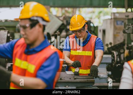 Asiatique technicien expert ingénieur masculin Focus détail de travail de précision de tournage de coupe manuelle fraisant la production de métaux dans l'industrie lourde Banque D'Images