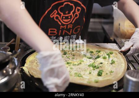 (170425) -- NEW YORK, 25 avril 2017 -- un membre du personnel fait un Jianbing au kiosque de M. Bing dans l'aire de restauration UrbanSpace à New York, aux États-Unis, le 17 avril 2017. UrbanSpace à Midtown New York est un endroit où les cols blancs viennent déjeuner pendant leurs journées de travail. Depuis quelques mois, les clients font toujours la queue devant un kiosque sous une bannière avec des caractères chinois. Ce que ce kiosque vend est une nourriture chinoise très authentique dans le nord de la Chine -- Jianbing, ou la crêpe chinoise. Le kiosque porte la marque MR. Bing et appartient à Brian Goldberg, qui est né et a grandi à New York. Goldberg est très moi Banque D'Images