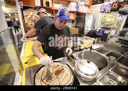 (170425) -- NEW YORK, 25 avril 2017 -- Brian Goldberg fait du jianbing au kiosque de M. Bing dans l'aire de restauration UrbanSpace à New York, aux États-Unis, le 17 avril 2017. UrbanSpace à Midtown New York est un endroit où les cols blancs viennent déjeuner pendant leurs journées de travail. Depuis quelques mois, les clients font toujours la queue devant un kiosque sous une bannière avec des caractères chinois. Ce que ce kiosque vend est une nourriture chinoise très authentique dans le nord de la Chine -- Jianbing, ou la crêpe chinoise. Le kiosque porte la marque MR. Bing et appartient à Brian Goldberg, qui est né et a grandi à New York. Goldberg est très inv Banque D'Images