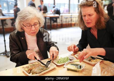 (170425) -- NEW YORK, le 25 avril 2017 -- les clients mangent le Jianbing de M. Bing dans l'aire de restauration UrbanSpace à New York, aux États-Unis, le 17 avril 2017. UrbanSpace à Midtown New York est un endroit où les cols blancs viennent déjeuner pendant leurs journées de travail. Depuis quelques mois, les clients font toujours la queue devant un kiosque sous une bannière avec des caractères chinois. Ce que ce kiosque vend est une nourriture chinoise très authentique dans le nord de la Chine -- Jianbing, ou la crêpe chinoise. Le kiosque porte la marque MR. Bing et appartient à Brian Goldberg, qui est né et a grandi à New York. Goldberg est très impliqué avec le chinois c Banque D'Images