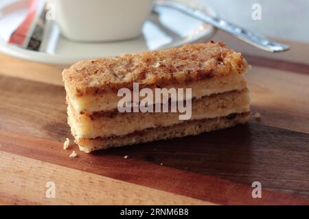 Tranche de pain à gâteau en couches de noix, couches d'éponge remplies de confiture et de crème avec nappage de noix et de blanc d'œuf Banque D'Images