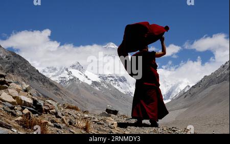 (170524) -- LHASSA, 24 mai 2017 -- Lama Ngawang Peljor regarde le mont Qomolangma au monastère de Rongpu dans la région autonome du Tibet du sud-ouest de la Chine, 17 mai 2017. Monastère de Rongpu, le monastère le plus haut du monde à plus de 5 000 mètres d'altitude, situé au pied du mont Qomolangma dans le comté de Tingri. Ngawang Peljor, âgé de 36 ans, pratique le bouddhisme dans le monastère depuis 15 ans. Il vit ici une vie monastique simple et régulière. Se levant à 8:30 heures du matin, il chante après le petit déjeuner jusqu'à midi. Il continue de chanter jusqu'à 4 heures après une pause d'une heure pour le déjeuner. Après le dîner, il se repose pour un hou Banque D'Images