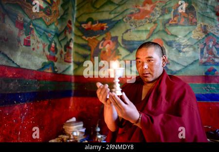 (170524) -- LHASSA, 24 mai 2017 -- Lama Ngawang Peljor lève une lampe à beurre au monastère de Rongpu près du mont Qomolangma, dans la région autonome du Tibet du sud-ouest de la Chine, 17 mai 2017. Monastère de Rongpu, le monastère le plus haut du monde à plus de 5 000 mètres d'altitude, situé au pied du mont Qomolangma dans le comté de Tingri. Ngawang Peljor, âgé de 36 ans, pratique le bouddhisme dans le monastère depuis 15 ans. Il vit ici une vie monastique simple et régulière. Se levant à 8:30 heures du matin, il chante après le petit déjeuner jusqu'à midi. Il continue de chanter jusqu'à 4 heures après une pause d'une heure pour le déjeuner. Après le dîner, lui Banque D'Images