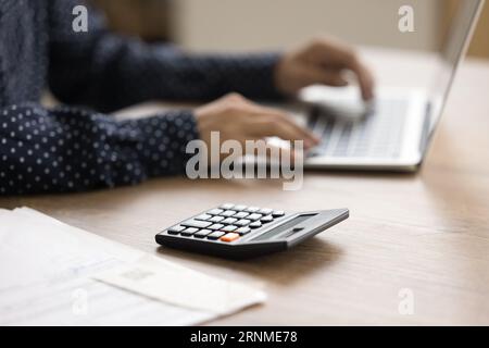 Calculatrice sur la surface de la table et vue rognée des mains féminines Banque D'Images