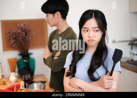 Offended young woman ignoring her upset husband after quarrel in kitchen. Negative emotions, relationship problems Stock Photo