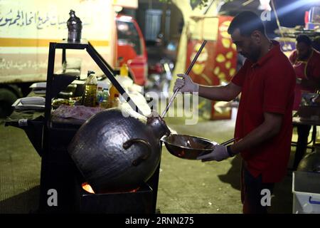 (170620) -- LE CAIRE, 20 juin 2017 -- un jeune homme égyptien prépare de la nourriture à un Bean Cart, un petit stand de nourriture de rue qui sert le repas traditionnel pré-jeûne, connu sous le nom de suhur, pendant le mois sacré musulman du Ramadan, sur le trottoir de la banlieue d'Héliopolis au Caire, en Égypte, le 19 juin 2017. Les charrettes à haricots uniques sont exploitées par un groupe de jeunes Égyptiens hautement instruits, qui espèrent utiliser une partie des revenus pour des activités caritatives. Le but principal de ce projet l'année dernière est la charité, a déclaré Hussein Hamza, un cofondateur de 30 ans du projet, à Xinhua. Le groupe ne travaille que pendant Ramada Banque D'Images