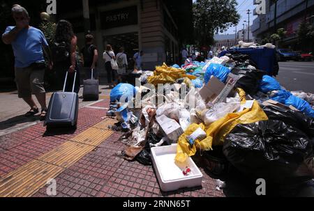 (170626) -- ATHÈNES, le 26 juin 2017 -- des gens passent devant une pile de déchets à Athènes, en Grèce, le 26 juin 2017. Des tonnes d'ordures s'accumulent à Athènes et dans d'autres grandes villes alors qu'une manifestation nationale contre les suppressions d'emplois appelée par les syndicats représentant les travailleurs municipaux de l'assainissement entrait dans sa deuxième semaine lundi.) GRÈCE-ATHÈNES-MANIFESTATION MariosxLolos PUBLICATIONxNOTxINxCHN Athènes juin 26 2017 des célébrités passent devant un tas d'ordures à Athènes Grèce LE 26 2017 juin, la tonalité des ordures s'accumule à Athènes et dans d'autres grandes VILLES en tant que protestation nationale contre les coupures d'emplois appelées par les syndicats représentant la Municipalité Banque D'Images