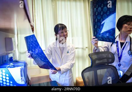 (170628) -- SHENZHEN, le 28 juin 2017 -- Lee Wing Mui Anne (L) vérifie le rapport de tomodensitométrie d'un patient à l'hôpital de l'Université de Hong Kong-Shenzhen à Shenzhen, dans le sud de la Chine, le 21 juin 2017. Lee, un médecin chinois de Hong Kong, est actuellement le chef du centre d'oncologie clinique de l'hôpital. Invitée par l'Université de Hong Kong, Lee a commencé son travail à l'hôpital en octobre 2012. Au cours des cinq dernières années, elle a voyagé de Hong Kong à Shenzhen deux jours par semaine, fournissant des services médicaux et participant à des travaux de gestion pour améliorer la coopération et la communication entre les médecins et les médecins Banque D'Images