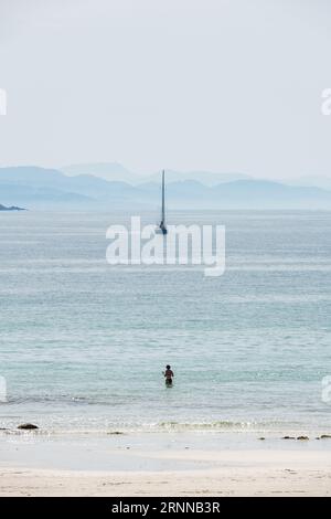 PONTEVEDRA, ESPAGNE - 8 AVRIL 2023 : une femme d'âge moyen solitaire sur une plage de la Ria de Pontevedra en Galice par un jour de printemps brumeux, avec un voilbo bleu Banque D'Images