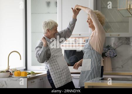 Heureux joyeux couple aîné actif dans des tabliers de formation à la danse sociale Banque D'Images