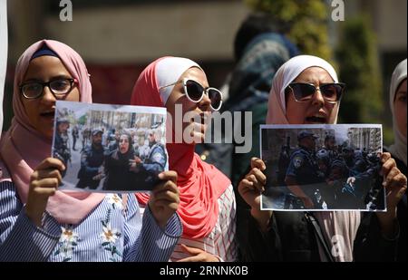 (170718) -- NAPLOUSE, 18 juillet 2017 -- des palestiniennes tiennent des photos de soldats israéliens attaquant des femmes dans la cour de la mosquée Al-Aqsa lors d'une manifestation contre la fermeture de l'enceinte de la mosquée Al-Aqsa à Jérusalem, dans la ville de Naplouse en Cisjordanie, le 18 juillet 2017. La mosquée Al-Aqsa a été fermée le 14 juillet après la mort de trois Palestiniens et de deux policiers israéliens dans une attaque armée. Israël a annoncé le 16 juillet la réouverture progressive de certaines des entrées de la mosquée Al-Aqsa, après avoir installé des portails électroniques, des caméras de surveillance et des équipements sensibles pour des raisons de sécurité Banque D'Images