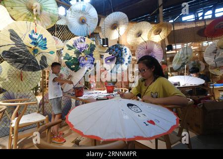 (170721) -- HANGZHOU, 21 juillet 2017 -- les enfants apprennent à fabriquer un parapluie en papier huileux dans une salle d'exposition artisanale près du Grand Canal à Hangzhou, province du Zhejiang dans l'est de la Chine, le 20 juillet 2017. Une ceinture culturelle et pittoresque, comprenant des musées, des zones culturelles et créatives, des reliques historiques et des rues anciennes, s'est formée le long de la section de 12 kilomètres du Grand Canal Pékin-Hangzhou dans le district de Gongshu à Hangzhou. )(MCG)(zt) CHINA-HANGZHOU-GRAND CANAL (CN) HuangxZongzhi PUBLICATIONxNOTxINxCHN Hangzhou juillet 21 2017 les enfants apprennent à faire le parapluie de papier d'huile DANS un hall d'exposition d'artisanat Banque D'Images