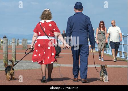 Morecambe, Lancashire - 2 septembre 2023 - les visiteurs ont apprécié le festival Vintage by the Sea de Morecambe samedi. Beaucoup d'entre eux sont venus vêtus de vêtements vintage. Un homme avait les mains pleines alors qu'il s'arrêtait pour se reposer après avoir marché cinq caniches. L'hôtel art déco Midland était rempli de spectateurs tandis que les véhicules rétro remplissaient les places de parking. Le festival a été béni avec un soleil glorieux et des températures chaudes. Les chanteurs divertissaient une petite foule sur des chaises longues au Melodrome. Crédit : Arrêter Press Media/Alamy Live News Banque D'Images