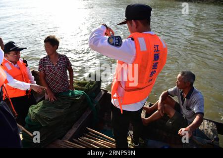 (170811) -- ANQING, 11 août 2017 -- des patrouilleurs auxiliaires vérifient un bateau de pêche dans la réserve naturelle de marsouin sans ailettes à Anqing, dans la province de l'Anhui de l'est de la Chine, 10 août 2017. Une brigade de patrouille auxiliaire, dont 6 anciens pêcheurs, a commencé sa mission le 2017 juin pour protéger les 60 marsouins sans ailettes le long de la section de 60 kilomètres du fleuve Yangtsé dans la province. L'application téléphonique est utilisée dans leurs missions de routine pour suivre et observer la vie des mammifères ressemblant aux dauphins, fournir la protection nécessaire et surveiller le polluant et la pêche illégale dans la réserve. ) (CLQ) CHINE-ANHUI-ANQING- Banque D'Images