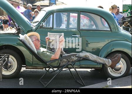 Morecambe, Lancashire - 2 septembre 2023 - les visiteurs ont apprécié le festival Vintage by the Sea de Morecambe samedi. Beaucoup d’entre eux sont venus habillés de vêtements vintage et se sont imprégnés de l’atmosphère. Un homme s'est reposé à l'ombre de sa voiture d'époque en lisant un journal alors que le soleil flamboyant se baissait. Crédit : Arrêter Press Media/Alamy Live News Banque D'Images