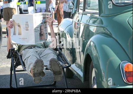 Morecambe, Lancashire - 2 septembre 2023 - les visiteurs ont apprécié le festival Vintage by the Sea de Morecambe samedi. Beaucoup d’entre eux sont venus habillés de vêtements vintage et se sont imprégnés de l’atmosphère. Un homme s'est reposé à l'ombre de sa voiture d'époque en lisant un journal alors que le soleil flamboyant se baissait. Crédit : Arrêter Press Media/Alamy Live News Banque D'Images