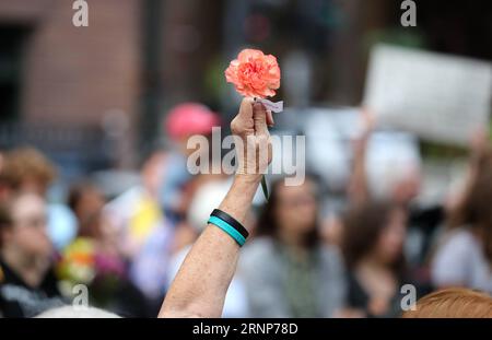 (170814) -- CHICAGO, 14 août 2017 -- Un participant lève une fleur lors d'une veillée en soirée au Federal Plaza à Chicago, aux États-Unis, le 13 août 2017. Plusieurs centaines de personnes se sont jointes à une veillée dimanche soir au Federal Plaza dans le centre-ville de Chicago, pour ceux qui ont été victimes des violences à Charlottesville en Virginie pendant le week-end.) (Zhf) U.S.-CHICAGO-CHARLOTTESVILLE-VICTIM-RALLYE WangxPing PUBLICATIONxNOTxINxCHN 170814 Chicago août 14 2017 un participant lève une fleur au cours de la veillée du soir À Federal Plaza à Chicago aux États-Unis LE 13 2017 août plusieurs centaines de Celebritie Banque D'Images