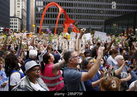 (170814) -- CHICAGO, 14 août 2017 -- des gens lèvent des fleurs lors d'une veillée en soirée au Federal Plaza à Chicago, aux États-Unis, le 13 août 2017. Plusieurs centaines de personnes se sont jointes à une veillée dimanche soir au Federal Plaza dans le centre-ville de Chicago, pour ceux qui ont été victimes des violences à Charlottesville en Virginie pendant le week-end.) (Zhf) USA-CHICAGO-CHARLOTTESVILLE-VICTIM-RALLYE WangxPing PUBLICATIONxNOTxINxCHN 170814 Chicago août 14 2017 célébrités élèvent des fleurs pendant la veillée du soir À Federal Plaza à Chicago les États-Unis LE 13 2017 août plusieurs centaines de célébrités se sont jointes à un dimanche e Banque D'Images