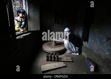 (170828) -- SRINAGAR, 28 août 2017 -- Une fille cachemirienne regarde un potier alors qu'il travaille avec de la boue pour faire du chillum traditionnel en terre dans un village du district de Budgam, à environ 25 km au sud-ouest de Srinagar, capitale d'été du Cachemire contrôlé par les Indiens, 28 août 2017. La communauté potter dans le Cachemire contrôlé par les Indiens perd ses moyens de subsistance en raison de l'évolution des modes de vie des habitants qui ne préfèrent plus les produits de poterie. Les enfants des potiers cachemiris ne prennent pas non plus à la profession car ils ne trouvent pas cela suffisant leurs besoins. ) (zw) KASHMIR-SRINAGAR-POTTERY JavedxDar PUBLICATIONxNOTxINxCHN Srin Banque D'Images