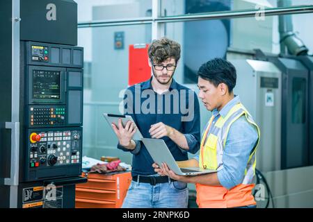 Smart expert senior ingénieur spécialiste masculin formation au travail jeune nouveau technicien opérateur de machine CNC moderne Banque D'Images