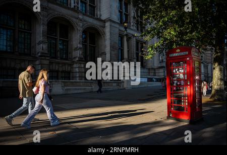 Londres, Royaume-Uni : les gens marchent sur le trottoir avec le soleil du soir projetant de longues ombres. Devant le Victoria and Albert Museum à South Kensington. Banque D'Images