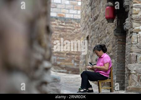 (170913) -- XINGTAI, 13 septembre 2017 -- le villageois Wang Chunxiang fabrique des chaussures en tissu dans une ruelle du village de Wangnao dans la ville de Xingtai, province du Hebei, dans le nord de la Chine, 12 septembre 2017. La renommée de l'ancien village de Wangnao repose sur son style d'architecture traditionnelle chinoise où les routes pavées de dalles de pierre, les maisons avec des murs de briques rouges et des tuiles bleu-vert. Plus de 130 bâtiments anciens sont bien conservés ici.) (wyl) CHINE-HEBEI-XINGTAI-ANCIEN VILLAGE (CN) ChenxLei PUBLICATIONxNOTxINxCHN Banque D'Images