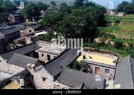 (170913) -- XINGTAI, 13 septembre 2017 -- Une femme distribue des grains sur le toit du village de Wangnao dans la ville de Xingtai, province du Hebei, dans le nord de la Chine, 12 septembre 2017. La renommée de l'ancien village de Wangnao repose sur son style d'architecture traditionnelle chinoise où les routes pavées de dalles de pierre, les maisons avec des murs de briques rouges et des tuiles bleu-vert. Plus de 130 bâtiments anciens sont bien conservés ici.) (wyl) CHINE-HEBEI-XINGTAI-ANCIEN VILLAGE (CN) ChenxLei PUBLICATIONxNOTxINxCHN Banque D'Images