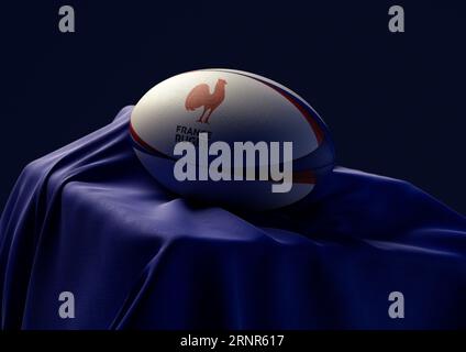 2 septembre 2023 - Bristol, Royaume-Uni : rendu 3D d'un ballon de rugby imprimé du logo France rugby reposant sur un tissu bleu drapé Banque D'Images