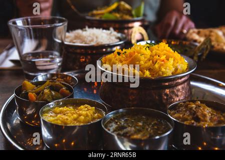 Homme mangeant de la nourriture traditionnelle dans un restaurant indien. Thali végétarien sur plateau, curry de poulet, riz, naan et autres plats délicieux sur table. Banque D'Images