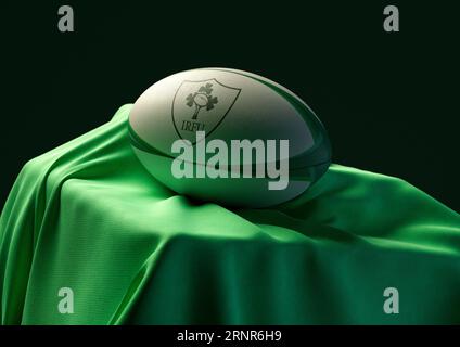 2 septembre 2023 - Bristol, Royaume-Uni : rendu 3D d'un ballon de rugby imprimé avec le logo de rugby irlandais reposant sur un tissu vert drapé Banque D'Images