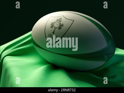 2 septembre 2023 - Bristol, Royaume-Uni : rendu 3D d'un ballon de rugby imprimé avec le logo de rugby irlandais reposant sur un tissu vert drapé Banque D'Images