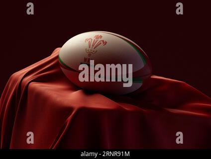 2 septembre 2023 - Bristol, Royaume-Uni : rendu 3D d'un ballon de rugby imprimé avec le logo de rugby du pays de Galles reposant sur un tissu rouge drapé Banque D'Images