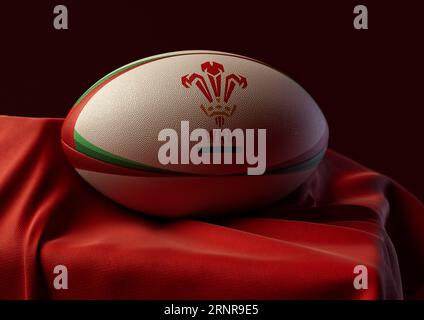 2 septembre 2023 - Bristol, Royaume-Uni : rendu 3D d'un ballon de rugby imprimé avec le logo de rugby du pays de Galles reposant sur un tissu rouge drapé Banque D'Images