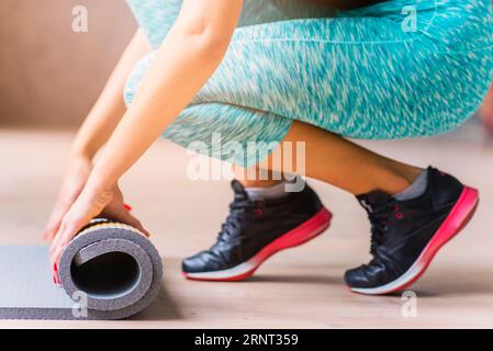 Gros plan femme main pliage tapis d'exercice Banque D'Images