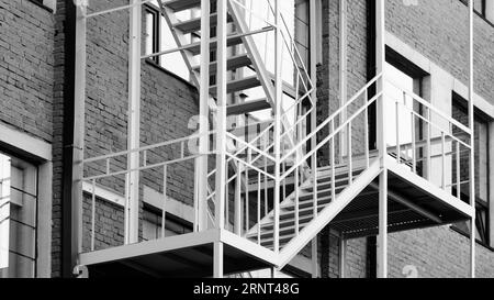 Escalier d'évasion de feu sur mur de bâtiment classique en brique rouge, ancien bâtiment industriel en briques rouges avec tuyaux de pluie en métal Banque D'Images