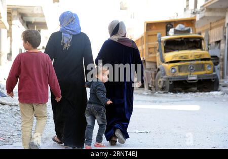 (171029) -- HOMS, 29 octobre 2017 -- des gens marchent dans un quartier ravagé de la ville d'al-Qarayatayn, province de Homs, centre de la Syrie, le 29 octobre 2017. L’armée syrienne a libéré la ville le 21 octobre 2017 après que les militants de l’État islamique (EI) l’aient prise d’assaut pour la deuxième fois le mois dernier. SYRIE-HOMS-VILLE LIBÉRÉE-VIE QUOTIDIENNE AMMARXSAFARJALANI PUBLICATIONXNOTXINXCHN Banque D'Images