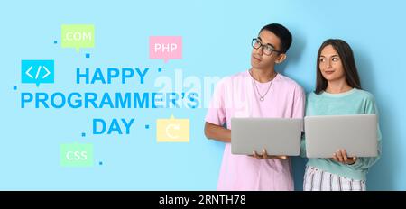 Jeune couple avec ordinateurs portables et texte HAPPY PROGRAMMER'S DAY sur fond bleu clair Banque D'Images